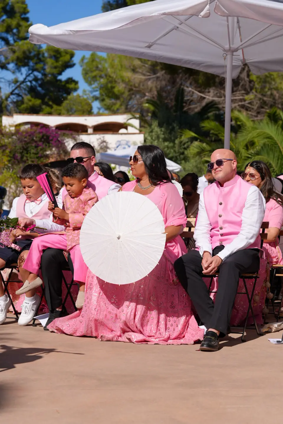 Outdoor wedding guests seated under a white parasol