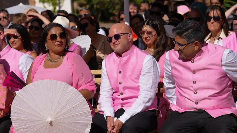 Outdoor wedding celebration scene with guests and greenery